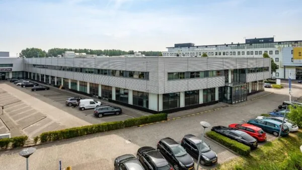 Kantoorgebouw aan de Rivium Boulevard met parkeerplaatsen en geparkeerde auto’s op de voorgrond.